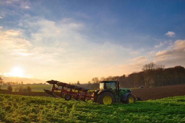 Tractor in the picturesque agricultural field at sunris, agriculture in Maransart, Lasne, Belgium A tractor in the picturesque agricultural field at sunris, agriculture in Maransart, Lasne, Belgium